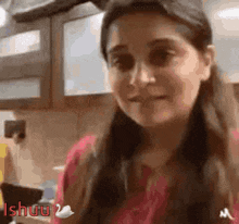 a woman in a red shirt is standing in a kitchen and smiling at the camera .