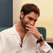 a man with a beard wearing a watch covering his mouth