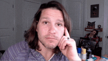 a man with long hair and a ring on his finger is looking at the camera