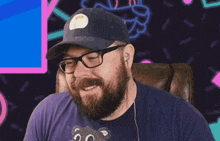a man with a beard and glasses is wearing a hat and holding a teddy bear .