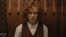a woman with red hair is making a funny face in front of a wooden wall that says prime on it