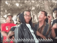 a group of young men are dancing in a park and one of them is wearing a hoodie and glasses .