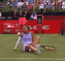 a woman sits on the court with a wilson racquet