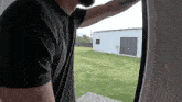 a man in a black shirt looks out a window