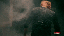 a man in a black shirt stands in a dark room with the word bull on the bottom