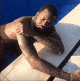 a man with a beard is laying on a ledge in a pool