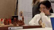 a woman playing chess in front of a sign that says federation monegasque des echecs
