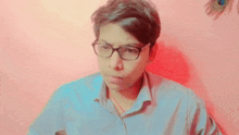 a young man wearing glasses looks at the camera
