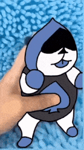 a person is holding a blue and white cartoon character on a blue carpet .