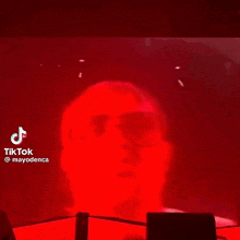a person is standing in front of a red wall with smoke coming out of it .