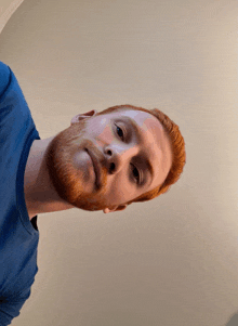 a man with red hair and a blue shirt is looking down
