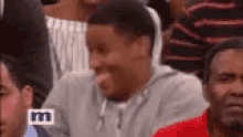 a man is sticking out his tongue while sitting in a crowd of people .