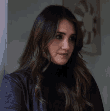 a woman with long dark hair wearing a black turtleneck sweater
