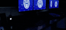 a dark room with three screens displaying a logo for the united states army