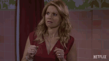 a woman in a red dress stands in front of a pink tiled wall with netflix written on it
