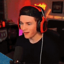 a man wearing headphones and a baseball cap is talking into a microphone .