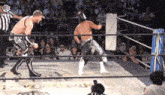 two wrestlers are fighting in a ring with a referee watching .