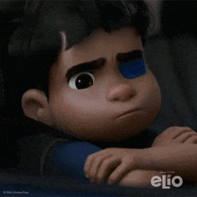 a boy with a blue patch on his eye is looking out a window with elio written on the bottom right