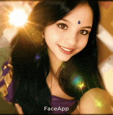 a woman with a blue bindi on her forehead is smiling in front of a faceapp logo