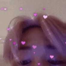 a close up of a person 's face with purple hair and pink hearts flying around .