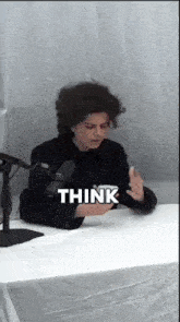 a person sitting at a desk with a microphone and the word think above them