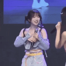 a girl is holding a microphone and smiling while standing next to another girl .