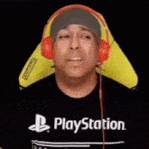 a man wearing headphones and a playstation shirt is sitting in a chair