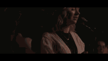 a woman singing into a microphone with a crowd behind her