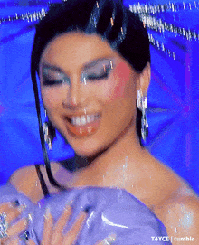 a close up of a woman wearing a purple dress and earrings is smiling .