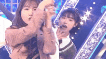 two girls are dancing on a stage with a microphone in their hands .