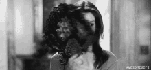a black and white photo of a woman blow drying her hair with a hair dryer .
