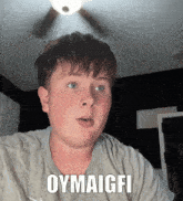 a boy wearing a grey shirt with the words oymaigfi on it