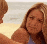a man and a woman are sitting on a beach looking at each other .