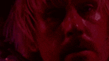 a close up of a man 's face in a red light with a red background .