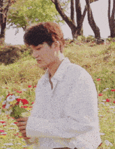 a young man in a white shirt is holding a bouquet of flowers