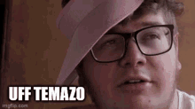 a man with glasses and a pink hat on his head is making a funny face .