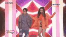 a man and a woman are dancing on a stage in front of a sign that says kapanaya