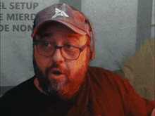 a man wearing glasses and a hat has a sign behind him that says " el setup "