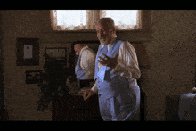 a man in a blue vest and tie stands in a room