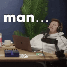 a man wearing headphones is sitting at a desk with a laptop and a microphone and the word man is written above him