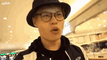 a young man wearing glasses and a hat is making a funny face .