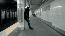 a person leaning against a pillar in a subway station with jordan ave written on the wall