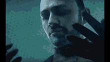 a close up of a man 's face with a hand behind it