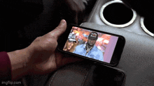 a person is holding a cell phone with a picture of a man and woman on it