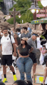 a woman with very large hips is standing in a crowd of people at an amusement park .