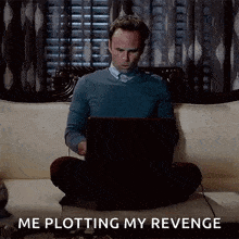 a man is sitting on a couch using a laptop computer and says me plotting my revenge .