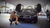 a man kneeling in front of a black bmw with the word aptis on the bottom
