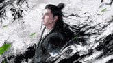 a man with long hair is standing in front of a painting of a tree .