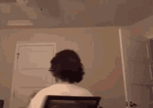 a man is sitting in a chair in a room looking at a computer screen .