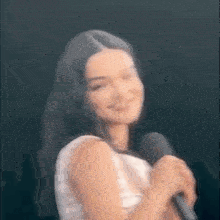 a woman is holding a microphone and smiling .